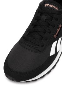 Czarny but sportowy z teksturowaną cholewką z tkaniny, z białymi paskami, czarnymi sznurowadłami i wyściełanym językiem. Logo Reebok w kolorze różowego złota.