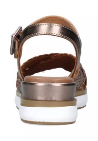 Sandali in pelle intrecciata marrone con un accento metallico bronzato, fascia posteriore e suola in gomma bianca. Presentano una semplice chiusura con fibbia.