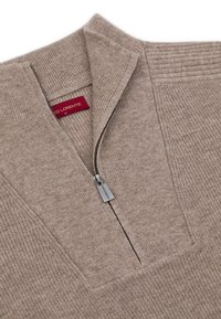 Beżowy sweter na zamek błyskawiczny z prążkowanym kołnierzem i fakturowanym materiałem. Posiada srebrny uchwyt zamka i czerwoną metkę marki wewnątrz kołnierza.