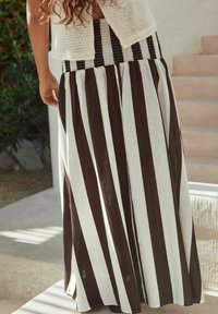 Jupe maxi en rayures noire et blanche, avec une taille smockée texturée. Tissu fluide avec un design léger et respirant.