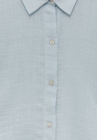 Camicia button-up azzurro chiaro realizzata in tessuto testurizzato con una finitura liscia. Dotata di colletto e cinque bottoni frontali.