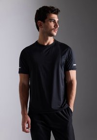 T-shirt atlética preta de manga curta, com textura suave e detalhes refletivos nos ombros. Design simples e ajustado, adequado para desporto.