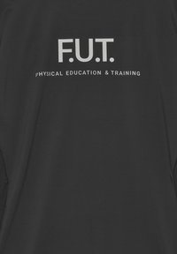 Svart sporttröja med en vit text som säger "F.U.T. FYSISK UTRUSTNING & TRÄNING." Tyget ser slätt och lätt ut.
