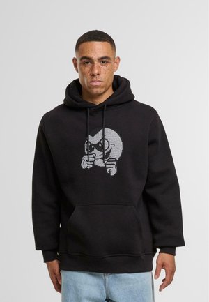 Zwarte hoodie met een grafisch ontwerp van een cartoonfiguur aan de voorkant. Het materiaal is zacht; de hoodie heeft een vo zak en koordjes.
