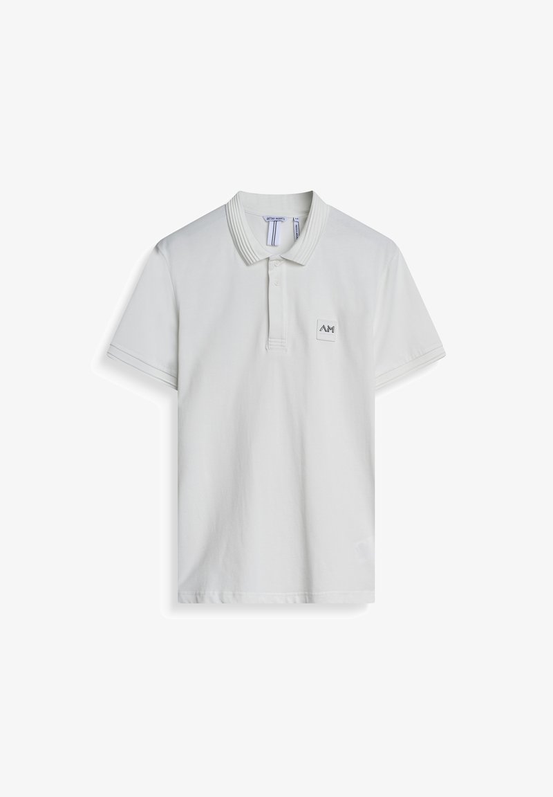 Bijela polo majica od pamuka, s rebrastim ovratnikom, kratkim rukavima i kvadratnom logotipnom zakrpom na lijevoj strani prsnog koša. Jednostavan dizajn.