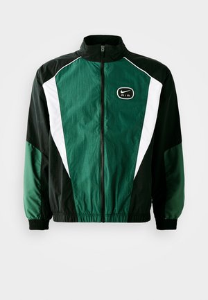 Nike-jack met een ritssluiting aan de voorkant, hoge kraag en een color-blocked ontwerp in donkergroen, zwart en wit met een geborduurd logo.