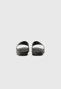 Sandale negre cu două curele late, talpă plată și căptușită, textură netedă și design minimalist. Fără branduri sau modele vizibile.