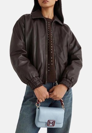Giubbotto bomber in pelle marrone con zip frontale e polsini a coste; abbinato a una borsa blu con clasp rettangolare e manico a catena.