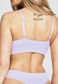 Ljust lila ribbad bralette med tunna justerbara axelremmar, med en rak rygg och en bred rem vid botten.
