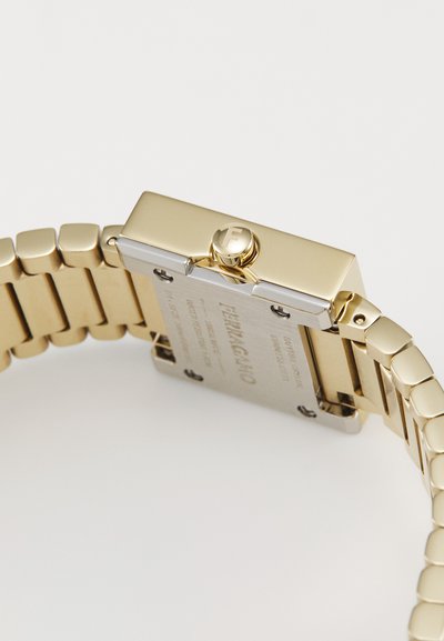Montre en acier inoxydable doré avec un cadran rectangulaire, un bracelet à maillons, des accents argentés et un logo bien en évidence sur la couronne. Gravures au dos.