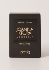 Czarny prostokątny pudełko z złotym tekstem. Z przodu widnieje napis "JOANNA KRUPA YOURSELF" oraz "EAU DE PARFUM 30 ML / 1 FL OZ" na dole.