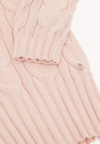 Suéter de punto trenzado en rosa claro, con puños y dobladillo acanalados. Incluye un pequeño detalle de logotipo plateado cerca de la parte inferior. Textura suave.