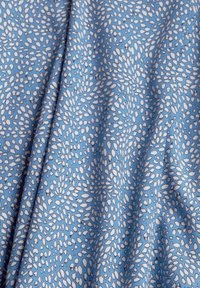 Tessuto blu con un motivo di foglie bianche sparse, caratterizzato da una texture morbida e un design leggero. Il motivo è astratto e distribuito uniformemente.