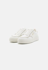 Sneaker bianche con superficie texturizzata, punta rotonda e suola a piattaforma spessa. Presentano dettagli beige e logo ricamato sul lato.