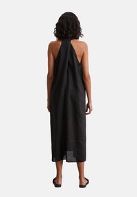 Schwarzes Halfterkleid aus leichtem Leinen, mit offenem Rücken und einer Midi-Länge, in einfachem, ungeschmücktem Design.