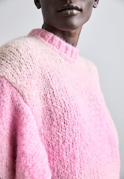 Maglione lavorato a maglia spessa in gradiente di rosa, con un alto collo a costine. Texture morbida con tonalità che vanno dal rosa chiaro a quello più scuro.