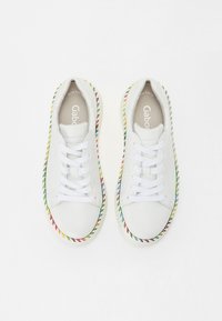 White leather sneakers featuring multicolored stitching along the sole, flat laces, and a cushioned insole visible inside.