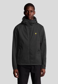 Sort zip-up jakke med hætte, der har elastiske manchetter, en glat tekstur og et lille gult logo på venstre bryst.