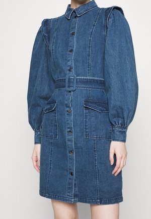 Vestido vaquero con mangas largas abullonadas, cierre frontal con botones, cintura con cinturón, dos bolsillos delanteros con solapa y cuello.