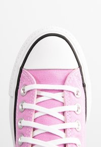 Rosa canvas sneakers med vita snören, svart gummitrim och vit tåhuvud. Texturerat material och klassisk snörningsdesign.