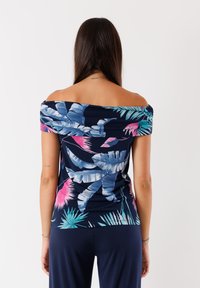Top blu navy a spalle scoperte con vivace stampa floreale tropicale. Presenta maniche corte e un design aderente. Realizzato in tessuto leggero e morbido.