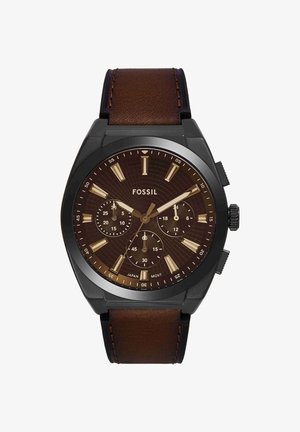 Ronde zwarte Fossil polshorloge met bruine wijzerplaat, gouden uurmarkeringen, drie subdials en een bruine leren band, die 9:10:38 aangeeft.
