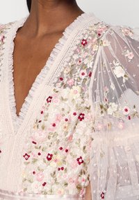 Robe à décolleté plongeant en V avec manches bouffantes transparentes, ornée d'une broderie florale complexe rose, blanche et rouge et de détails en dentelle.