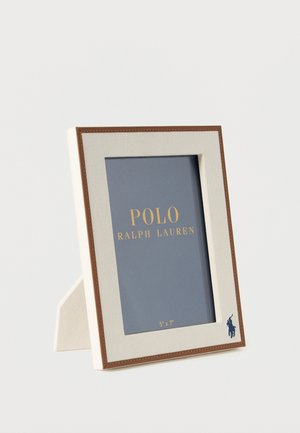 Suorakulmainen kerma-valkoinen valokuvakehys ruskealla reunuksella ja Polo Ralph Lauren -logolla, seisoo tasaisella pinnalla ja pitää sisällään 5x7 tuuman paikkamerkin.