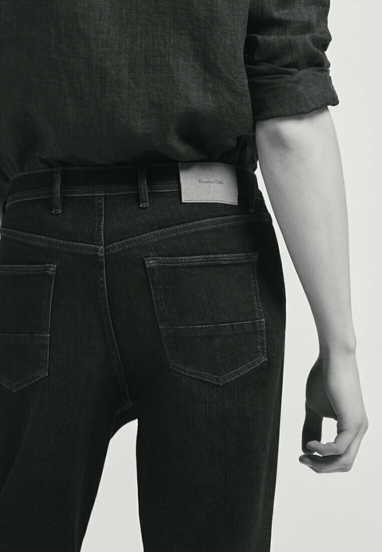 Svarta denimjeans med en figurnära design, med bakfickor och en ljusgrå märkeslapp i midjan. Tyget har en jämn textur.