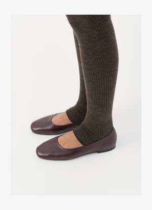 Burgundski lakirani balerini s kvadratnim vrhom, uparen sa tamnosmešnim rebrastim čarapama koje dosežu do sredine listova.