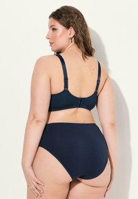 Navy blue stanik i majtki z wysokim stanem, wykonane z miękkiego materiału. Regulowane ramiączka i zapięcie na plecach. Gładkie tekstury, minimalne zdobienia.