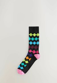 Farverig sort sok med bølgemønstre i grøn, blå, pink, lilla og orange, med en lys pink tå og ribbet manchet.