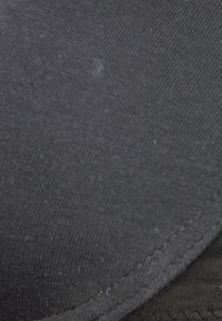 Tissu noir avec une surface texturée et des coutures visibles. Présente une finition lisse avec des nuances légèrement variées de noir.