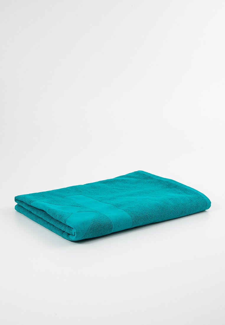 Asciugamano da bagno turchese, piegato, realizzato in cotone testurizzato. Presenta un colore solido e liscio con un delicato motivo a righe lungo un bordo.