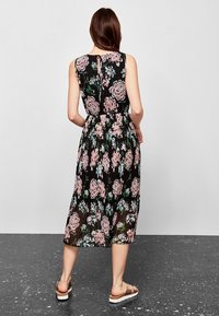 Schwarzes floral Midi-Kleid mit ärmellosem Design, das große rosa und grüne Rosen, plissierten Stoff und ein Schlüsselrücken-Detail aufweist.