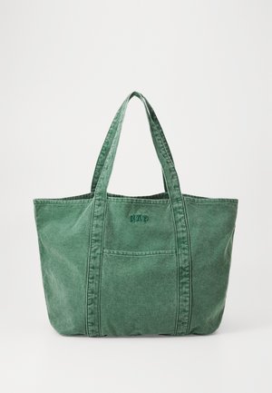 Grøn kanvas tote bag med to solide håndtag, forlomme og broderet logo. Blød tekstur med forstærket syning og rene linjer.