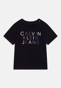 T-shirt nero a maniche corte con scollo rotondo. Presenta "CALVIN KLEIN JEANS" in lettere multicolori: crema, amaranto e blu.