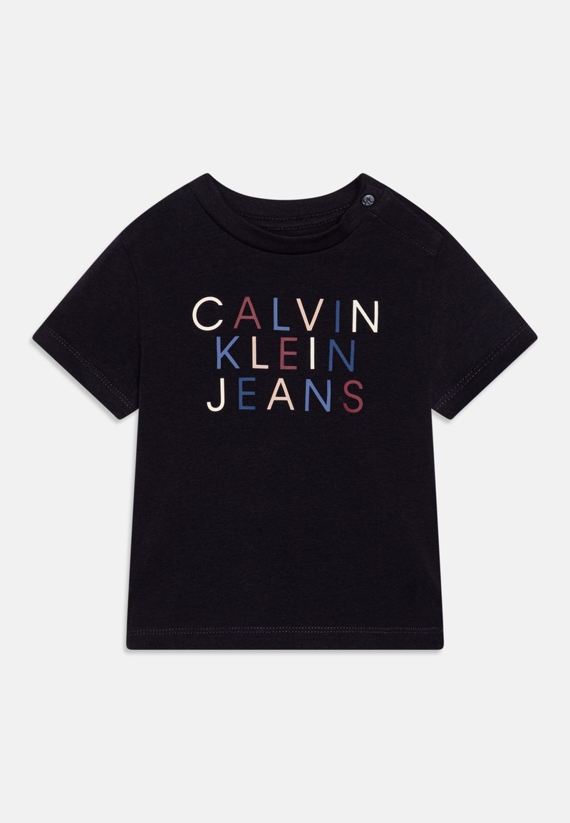 T-shirt nero a maniche corte con scollo rotondo. Presenta "CALVIN KLEIN JEANS" in lettere multicolori: crema, amaranto e blu.