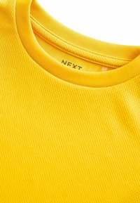Gul mesh t-shirt med rund halsudskæring og tekstureret overflade. Mærkeskilt "NEXT" synligt indeni kraven.