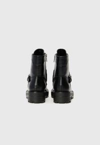Sorte lær ankle boots med en kraftig gummisåle, som har glidelåser på siden og metalldetaljer, glatt tekstur og enkelt design.