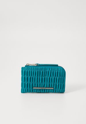 Teal zippered wallet with a quilted texture, featuring a silver hardware accent on the front, compact and rectangular design.