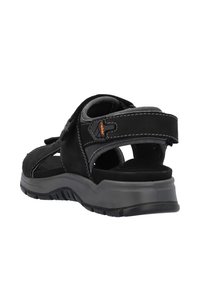 Sandale noire avec une tige en daim, une lanière ajustable et une semelle intérieure grise rembourrée. Semelle en caoutchouc texturée avec un léger talon pour une meilleure adhérence.