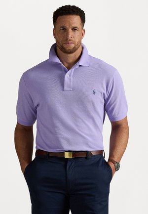 Tricou polo de culoare mov deschis, cu guler texturat, placket cu două butoane și un mic logo navy. Purtați cu pantaloni închiși la culoare și o curea maro.
