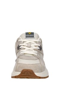 Vue de face d'une basket beige et blanche Lyle & Scott avec des lacets blancs et une semelle en caoutchouc marron.