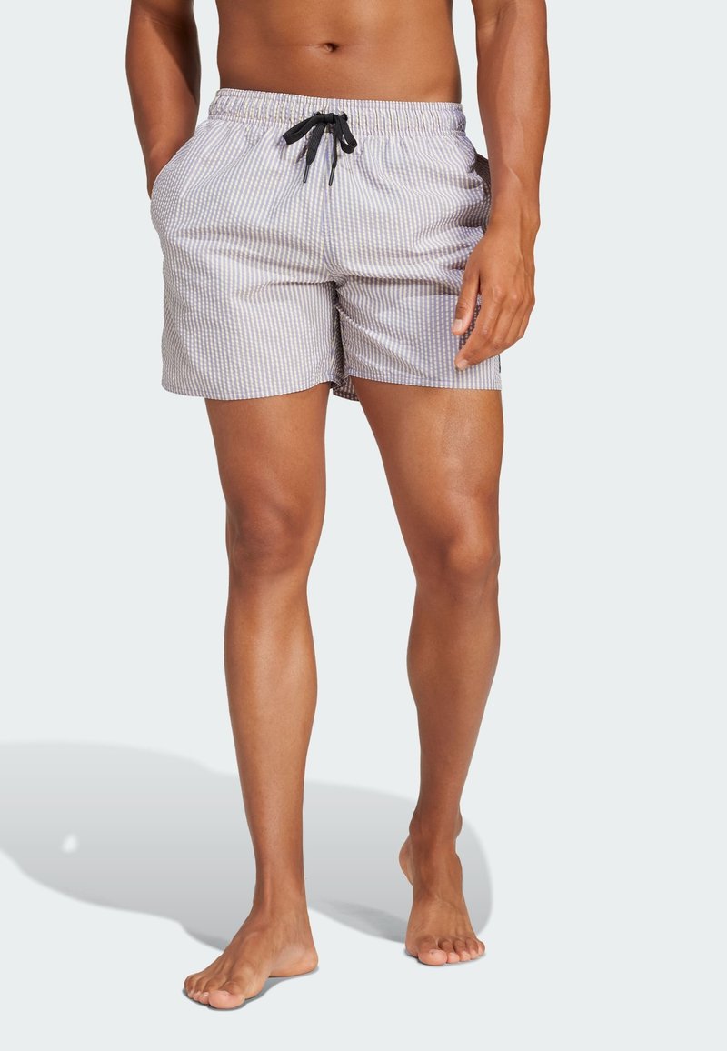 Costume da bagno da uomo in un leggero grigio con motivo a strisce bianche, dotato di una cintura elastica con un laccio nero. Due tasche laterali.