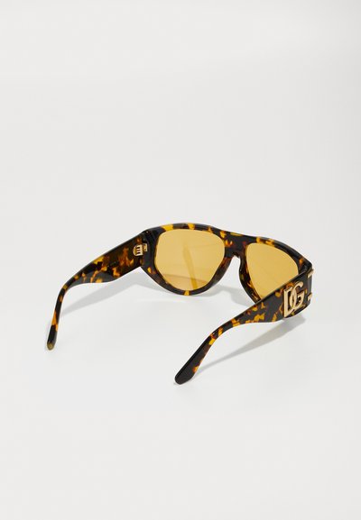 Ochelari de soare cu model scoică, cu lentile galbene, design unghiular și detaliu cu logo auriu pe brate, având o finisare lucioasă.