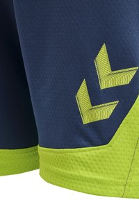 Pantaloni sportivi blu navy con tessuto testurizzato, dotati di dettagli verde lime e di un design a strisce diagonali contrastanti vicino all'orlo.