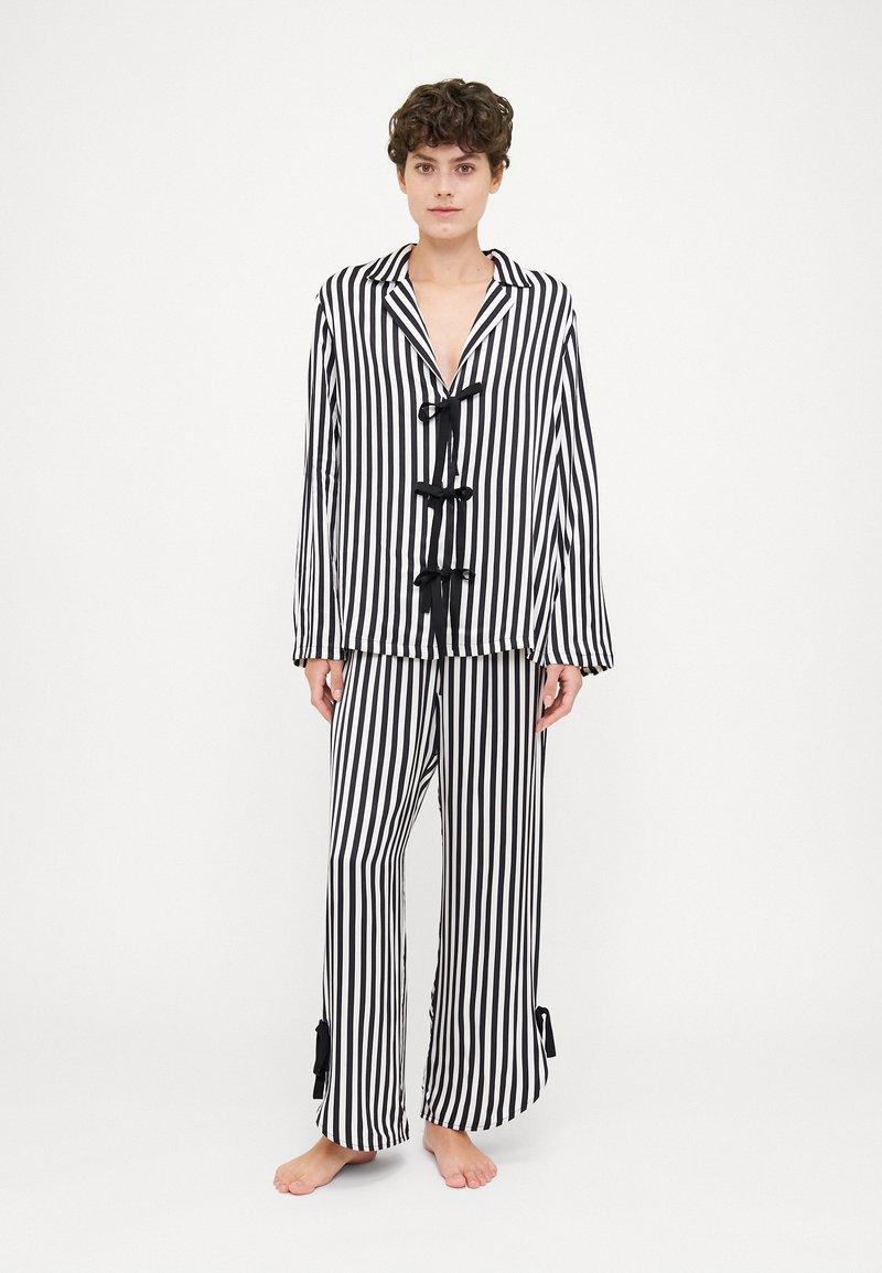 Black and white striped loungewear set with a button-up top featuring three black bows and loose-fitting pants with ribbon accents at the hem.
