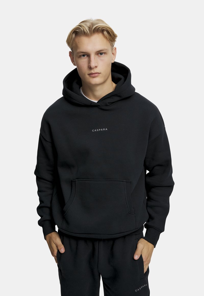 Mustat hupparit, jotka on valmistettu pehmeästä kankaasta, jossa on kengurupocket, ribatut hihansuut ja keskiössä oleva logo. Yhdistettynä samansävyisiin mustiin housuihin.