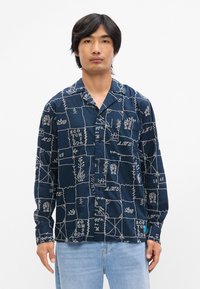 Σκού ρο μπλε πουκάμισο με λευκά κεντημένα σχέδια, με γιακά και μακριά μανίκια, φτιαγμένο από ελαφρύ, υφασμένο ύφασμα.